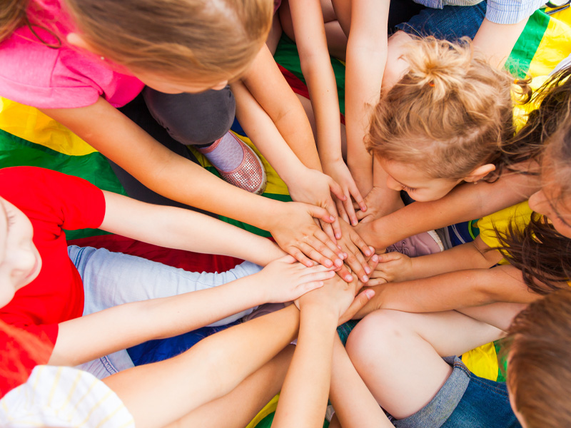 Das Bild eine mehrere Kinder von oben betrachtet, die im Kreis angeordnet Ihre Hände in der Mitte stapeln.