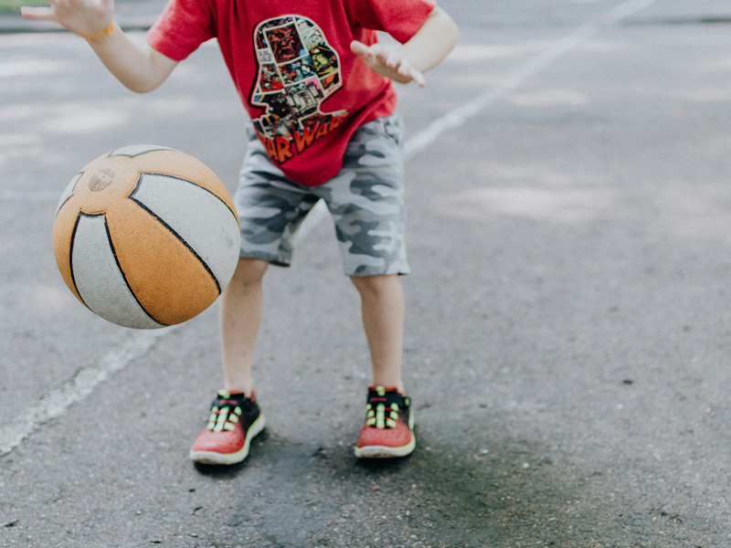 Ein kleiner Junge hat Spaß beim Basketballspielen und zeigt seine Begeisterung für den Sport.