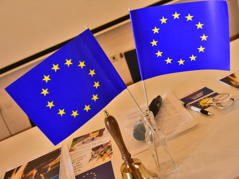 Auf einem Tisch angeordnete Flaggen der Europäischen Union, die die Vielfalt und Einheit der Mitgliedsländer repräsentieren.