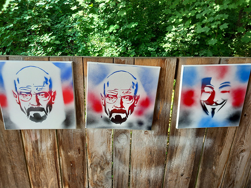 Das Bild zeigt drei verschiedene Gesichter die auf eine Leinwand gesprayt wurden.