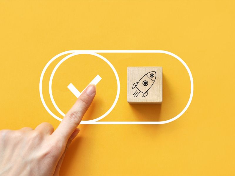 Das Bild zeigt eine Hand mit einem ausgestreckten Zeigefinger, der einen Check-Haken auf gelben Hintergrund antippt.