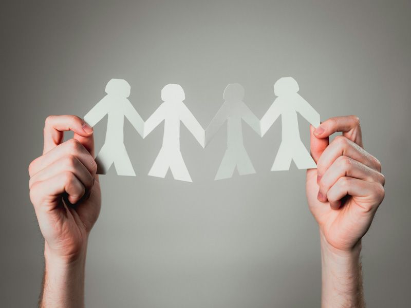Hände halten ausgeschnittene Papierfiguren, die symbolisch für Gemeinschaft und Zusammenhalt stehen.