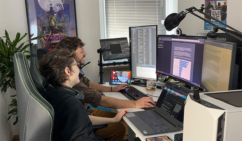 Das Bild zeigt einen Schreibtisch mit orangener Oberfläche, die Tastatur eines Laptops, einen Taschenrechner sowie einen Block mit Bleistift