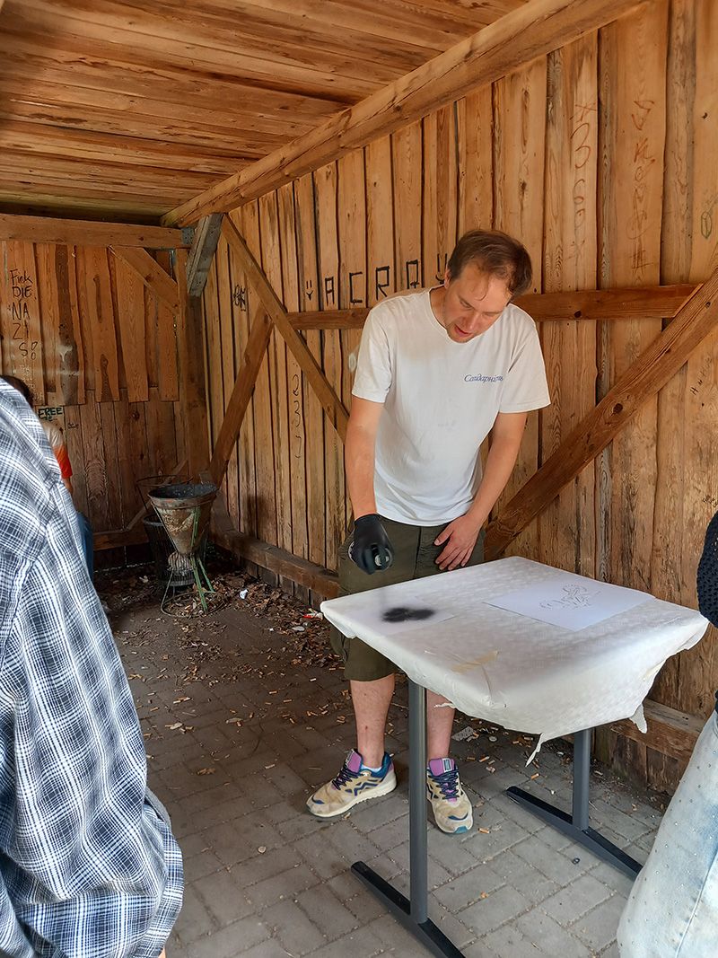Das Bild zeigt eine Person, der mit einer Spraydose auf eine Leinwand sprüht.